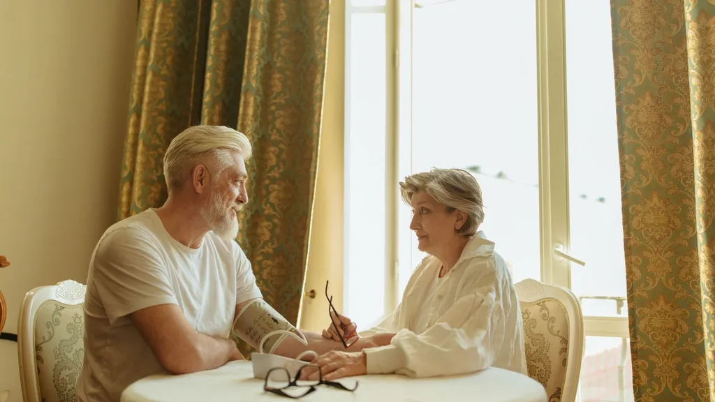 An older couple using a digital blood pressure monitor together at home