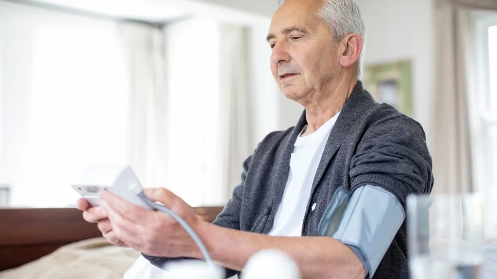 Older adult using a connected blood pressure monitor at home